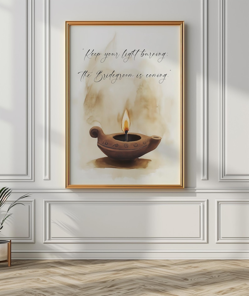May include: A framed art print featuring a watercolor painting of a brown oil lamp with a lit flame. The artwork includes the text "Keep your light burning: The Bridegroom is coming." The frame is gold, and the background is a soft, neutral color.