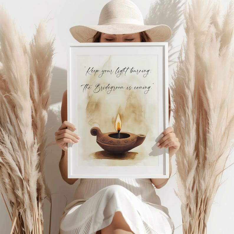 May include: A framed print featuring a watercolor illustration of a lit oil lamp. The artwork has a warm color palette with the text "Keep your light burning. The Bridegroom is coming." The frame is white.