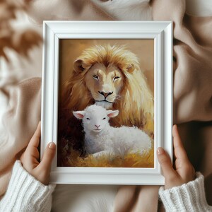 May include: A framed painting of a lion and a lamb. The lion has a golden mane and is looking at the lamb. The lamb is white and is looking up at the lion. The background is a soft golden color.