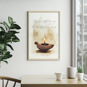 May include: A framed print featuring a watercolor illustration of a brown oil lamp with a lit flame. The artwork includes the text "Keep your light burning. The Bridegroom is coming." The print is displayed on a wall near a window.