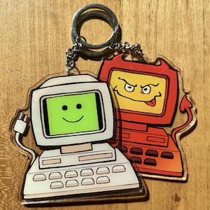 Peut inclure: Un porte-clés en forme d'ordinateur blanc et rouge avec un visage souriant et un visage diabolique. Le porte-clés est en acrylique et possède un anneau métallique pour l'attacher aux clés.