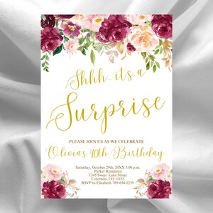 Peut inclure: Carte d'invitation blanche ornée de motifs floraux bordeaux, roses et pêche. L'écriture dorée dit "Shhh... it's a Surprise" et les détails de la célébration du 40e anniversaire d'Olivia. Comprend la date, l'heure, le lieu et les informations RSVP.