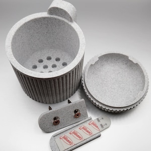 May include: A white, textured, cylindrical planter with a removable lid and a drainage hole. The planter comes with two mounting brackets and Command brand adhesive strips.