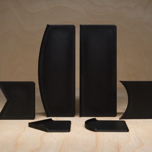 May include: A set of six black plastic puzzle pieces. The pieces are shaped like different geometric shapes, including squares, rectangles, and triangles.