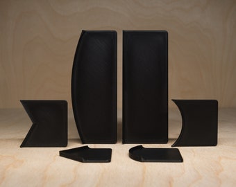 May include: A set of six black plastic puzzle pieces. The pieces are shaped like different geometric shapes, including squares, rectangles, and triangles.
