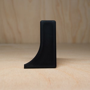 May include: A black plastic corner brace with a curved edge.