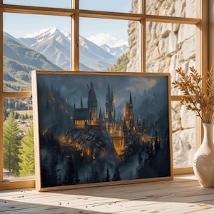 May include: A framed print of a castle on a mountain, with a wooden frame. The artwork depicts a detailed, illuminated castle with multiple towers, set against a backdrop of a misty forest and mountains. The print is displayed on a wooden surface near a window.