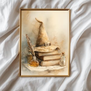 May include: Watercolor print of a witch's hat, books, and potion bottles. The hat is tan with a buckle, resting atop a stack of three aged books. A feather and bottles of potions complete the magical scene, framed in gold.