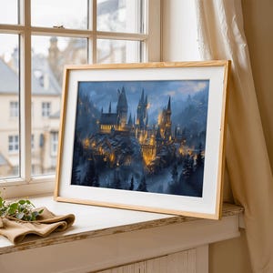 May include: A framed print of a castle with illuminated towers and spires, set against a misty, mountainous backdrop. The artwork is in a light wood frame, resting on a windowsill with a neutral-toned cloth and greenery.