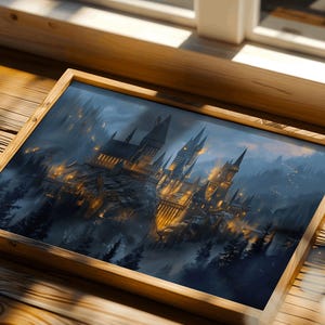 May include: A framed print of a castle with multiple towers, set against a misty, dark blue sky. The castle is illuminated with warm, golden lights, and surrounded by dark green trees. The frame is made of light brown wood.