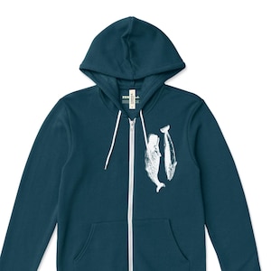 May include: Teal zip-up hoodie with a white whale graphic. The hoodie has a hood, a full-length zipper, and two front pockets. The graphic features two whales. The brand logo "ZEN THREADS" is in the bottom right corner.