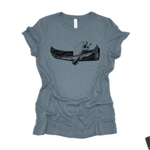 May include: A heather blue t-shirt with a black and white illustration of a beaver paddling a canoe.