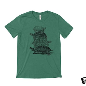 May include: Green t-shirt with a black and white illustration of turtles stacked on top of each other. The shirt has a crew neck and short sleeves. The brand "Zen Threads" is printed in black on a white background.
