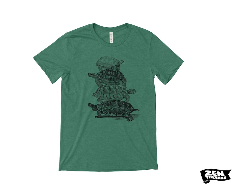 May include: Green t-shirt with a black and white illustration of turtles stacked on top of each other. The shirt has a crew neck and short sleeves. The brand "Zen Threads" is printed in black on a white background.