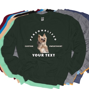 Puede incluir: Una colecci&oacute;n de sudaderas de manga larga en varios colores, incluyendo verde oscuro, gris y azul. Cada sudadera presenta un dise&ntilde;o personalizado con una imagen de perro y el texto "PERSONALIZED SWEATSHIRT" y "YOUR TEXT".