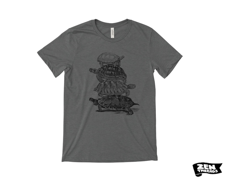 May include: Charcoal grey t-shirt with a black and white graphic of turtles piled up. The shirt has a crew neck and short sleeves. The brand logo "ZEN THREADS" is in the bottom right corner.