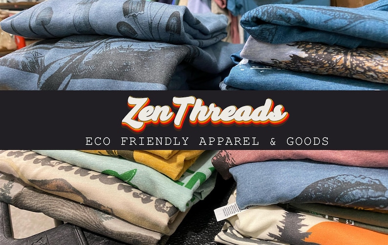 Pode incluir: Uma pilha de camisetas dobradas com v&aacute;rios desenhos e cores. As camisetas est&atilde;o empilhadas em uma mesa com uma faixa preta que diz "Zen Threads ECO FRIENDLY APPAREL & GOODS".
