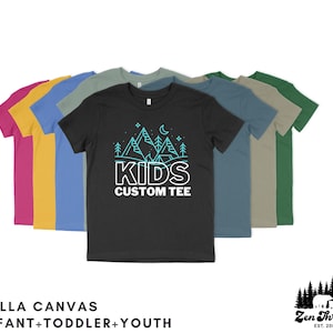 May include: A collection of colorful t-shirts for kids, featuring a black tee with a turquoise mountain and tent design and the words "KIDS CUSTOM TEE". The shirts are available in various sizes, including infant, toddler, and youth.