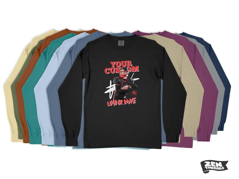 Pode incluir: Uma camiseta preta de manga comprida com um gr&aacute;fico vermelho e branco de um jogador de futebol americano. O texto "YOUR CUSTOM LOGO OR IMAGE" &eacute; impresso abaixo do gr&aacute;fico. A camiseta &eacute; mostrada com uma variedade de op&ccedil;&otilde;es de cores.