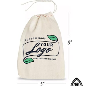 Op de afbeelding: Een witte katoenen trekkoordtas met een rode stiksel rond de bovenkant. De tas is 8 inch hoog en 5 inch breed. Het heeft een groen bladerenontwerp en de tekst "CUSTOM BAGS YOUR Logo PRINTED BY ZEN THREADS".
