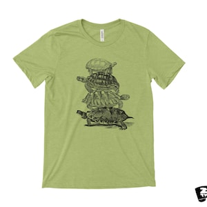 May include: A pale green t-shirt with a black and white drawing of turtles piled up. The top has a crew neck and short sleeves. The brand logo "ZEN THREADS" is in the bottom right corner.