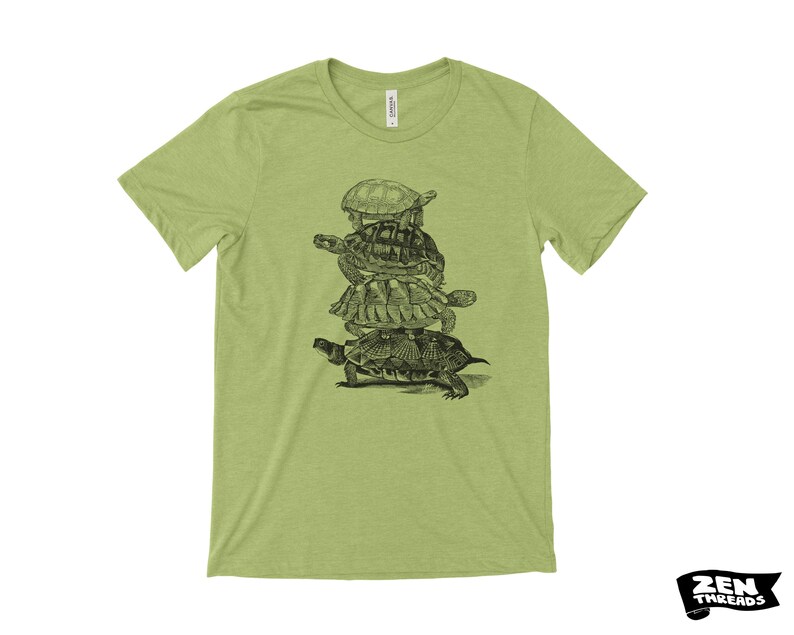 May include: A pale green t-shirt with a black and white drawing of turtles piled up. The top has a crew neck and short sleeves. The brand logo "ZEN THREADS" is in the bottom right corner.