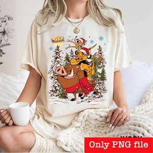 May include: Cream-colored t-shirt featuring a festive illustration of characters from The Lion King. Simba, Timon, and Pumbaa are depicted with Christmas lights and Santa hats. The text "Only PNG file" is at the bottom.