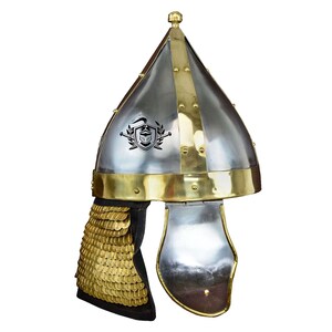 May include: A silver and gold helmet with a pointed top and a chainmail neck guard. The helmet has a decorative design on the front.