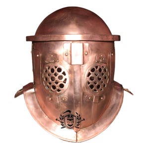 May include: A copper-coloured gladiator helmet with a decorative design and a mesh face guard. The helmet has a rounded top and a pointed chin guard.