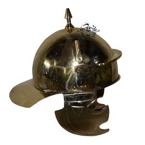 May include: A gold-colored helmet with a pointed top and a visor. The helmet has a decorative design on the side.