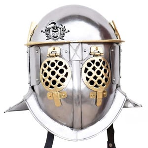 May include: A silver gladiator helmet with a brass trim and a brass grill over the eyes. The helmet has a crest with a knight and a sword.