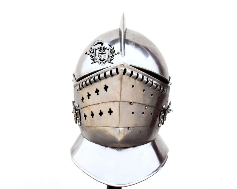 May include: A silver knight's helmet with a crest and a visor. The helmet has a decorative design with small crosses on the front.