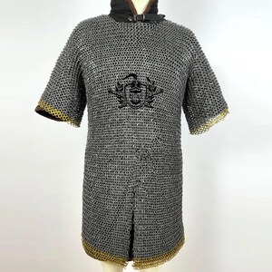 May include: A gray chainmail shirt with short sleeves and a gold trim. The shirt has a crest on the front.