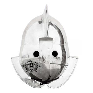 Puede incluir: Un casco plateado con una cresta puntiaguda y dos agujeros para los ojos. El casco tiene un diseño decorativo en la parte delantera.