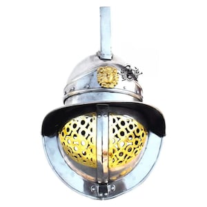 Puede incluir: Un casco de gladiador plateado y dorado con un diseño de cabeza de león en la parte superior. El casco tiene una máscara facial con un diseño de malla dorada.