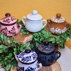 May include: Four ceramic serving dishes with lids. The dishes are decorated with white and blue floral patterns. The lids are white with a floral pattern. The dishes are on a wooden surface.