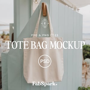 Könnte beinhalten: Beige Tragetaschen-Mockup, das an einem Holzhaken vor einer hellblauen Wand hängt. Der Beutel hat ein schlichtes Design mit dem Text "TOTE BAG MOCKUP" und "PSD & PNG FILES" in Weiß. Das FabSpark-Logo ist unten zu sehen.