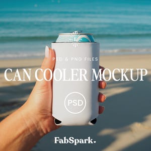 Puede incluir: Una maqueta de enfriador de latas blanca sostenida contra un fondo de playa. El enfriador tiene forma cilíndrica y una base negra. El texto "CAN COOLER MOCKUP" se muestra en blanco, junto con "PSD & PNG FILES" y el logotipo de FabSpark.