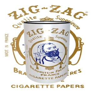 May include: A white can with a gold Zig Zag logo and a cartoon man with a beard holding a cigarette. The can says "Qualite Superieure" and "Braunstein Freres France Cigarette Papers".