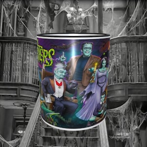 May include: A white ceramic mug with a black rim features a colourful illustration of the Addams Family characters. The mug has the words "The Munsters" printed on it.