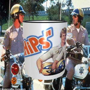 May include: A white ceramic mug with a black rim and a blue and orange "CHiPs" logo. The mug features a picture of a man wearing a police uniform and holding a motorcycle helmet.