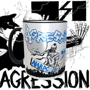 May include: White ceramic mug with a black handle. The mug has a black rim and a graphic of a zombie-like figure holding a skateboard with the word "NARACAE" on it. The background of the graphic is a black and white illustration of a graveyard with a full moon. The word "AGGRESSION" is written in blue letters across the top of the mug.