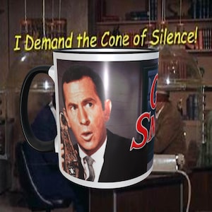 May include: A white coffee mug with a black handle and black rim. The mug features a color image of a man on a phone with the text "Get Smart" in red letters. The text "I Demand the Cone of Silence!" is printed above the mug.