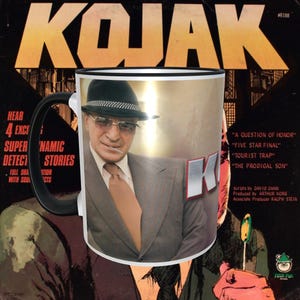 Op de afbeelding: Een witte keramische mok met een zwart handvat heeft een kleurenfoto van acteur Telly Savalas als Detective Kojak. De mok heeft een zwarte rand en een zilveren metallic glans. De afbeelding toont Kojak in een bruin pak, een wit overhemd, een bruine stropdas en een zwarte fedora-hoed. Hij houdt een lolly in zijn rechterhand. De tekst "KOJAK" is in grote, vetgedrukte, zwarte letters op de mok gedrukt.