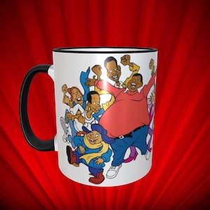 May include: White ceramic mug with a black rim and handle. The mug features a cartoon image of a group of people, including a large man in a red shirt and blue jeans, and a smaller person in a blue coat and yellow scarf. The characters are all smiling and appear to be dancing.