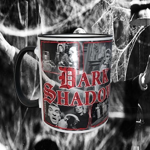 May include: A black and white mug with a collage of images from the television show "Dark Shadows". The mug has a black handle and a white rim. The text "Dark Shadows" is printed in red on the mug.