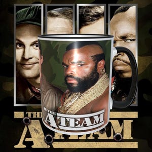 May include: A silver mug with a black handle and a black rim. The mug has a picture of Mr. T from the A-Team on it. The mug has the words "The A-Team" printed on it.