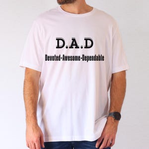 Op de afbeelding: Wit T-shirt met zwarte tekst die "D.A.D. Devoted-Awesome-Dependable" luidt