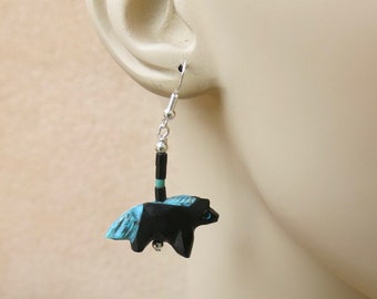 Op de afbeelding: Oorbellen met een hanger van sterling zilver met een gegraveerde zwarte beer met turquoise accenten.