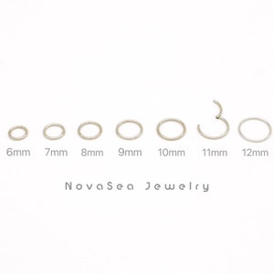 Puede incluir: Un conjunto de 7 aros de plata en varios tamaños, que van de 6 mm a 12 mm. Los aros se muestran sobre un fondo blanco con el texto "NovaSea Jewelry" debajo.